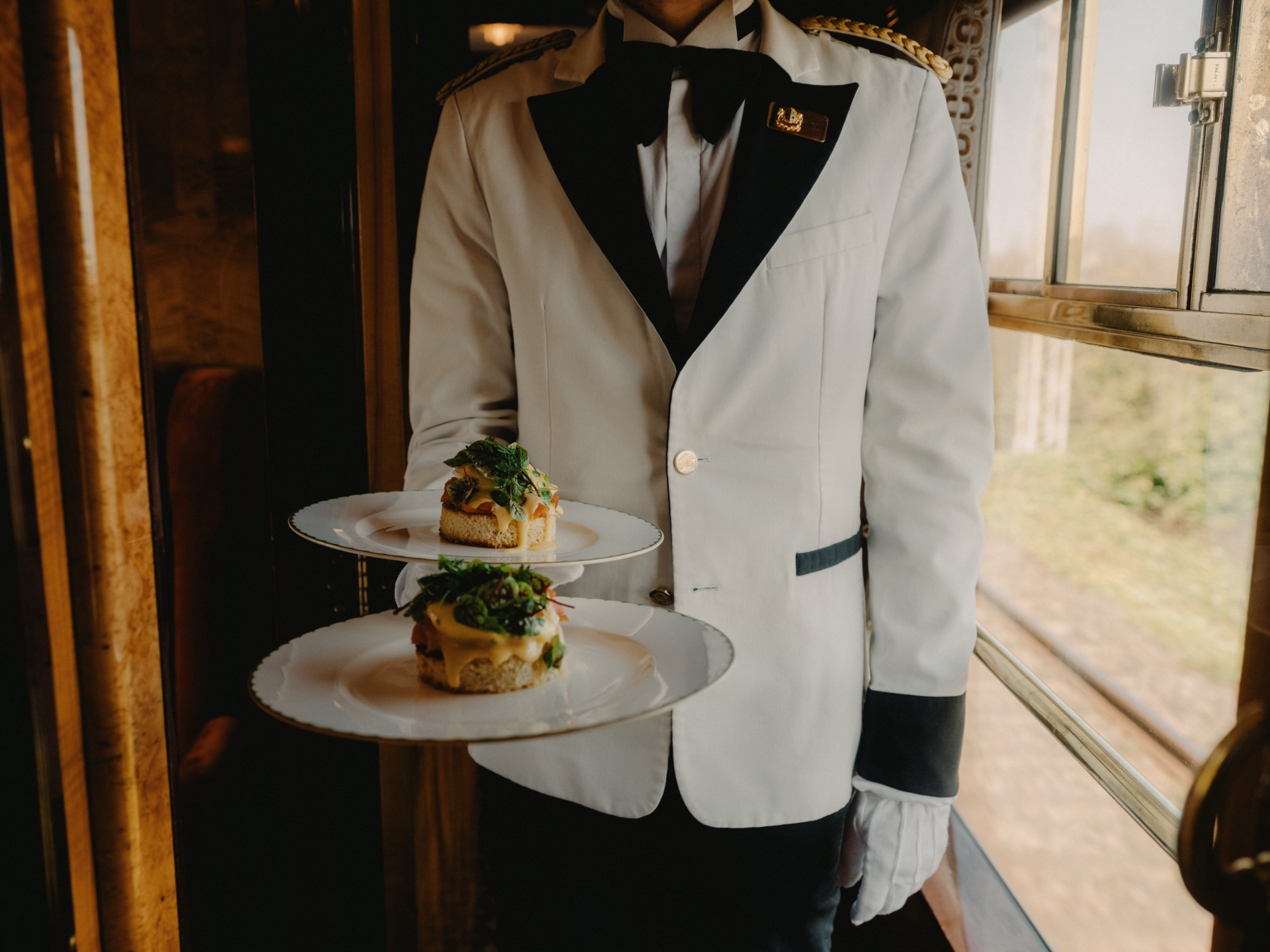 Belmond British Pullman steward serving fine champagne and luxury Sunday roast onboard
