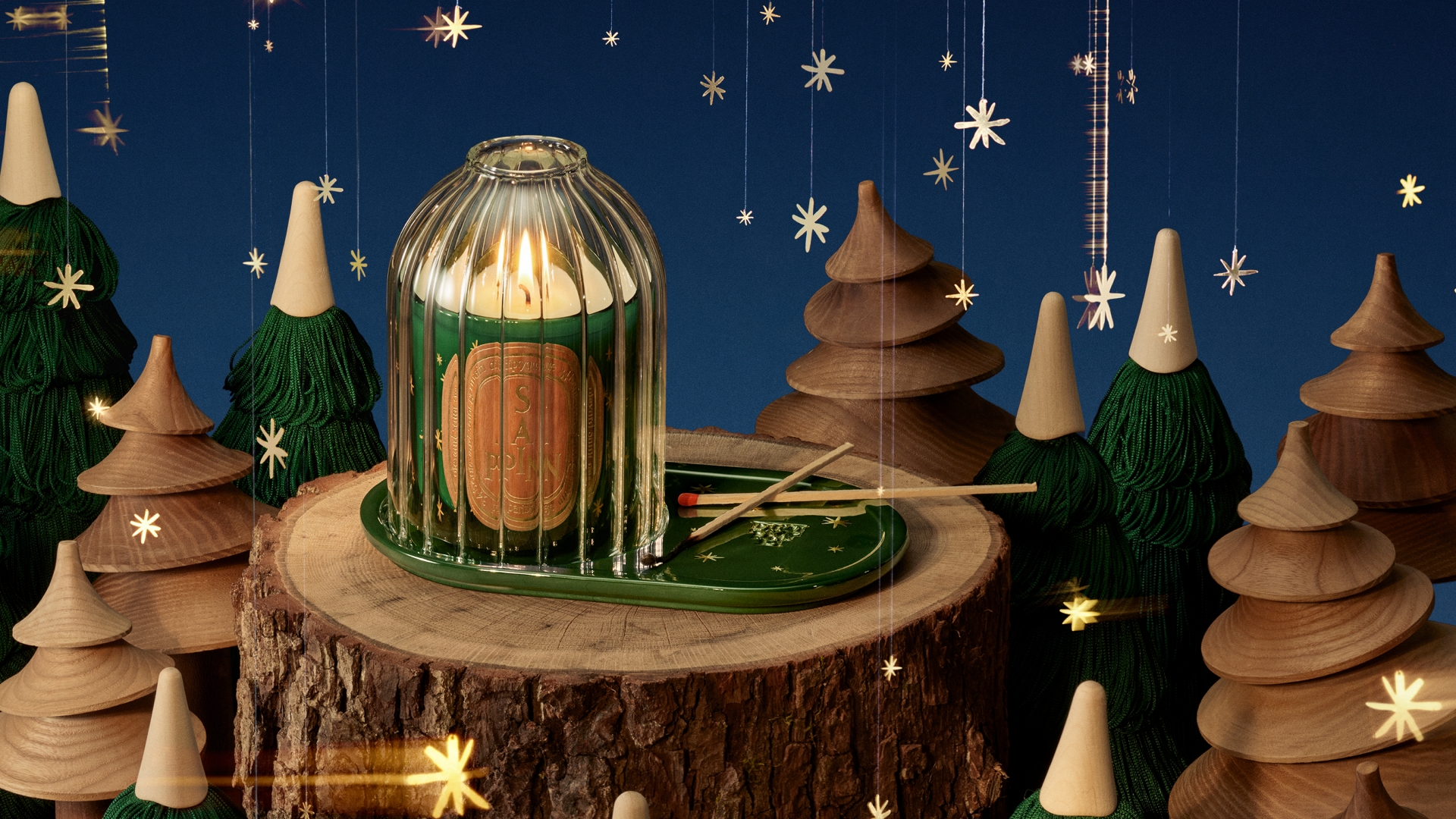 A limited-edition Diptyque Sapin candle in a festive green jar, accompanied by a decorative golden carousel accessory.