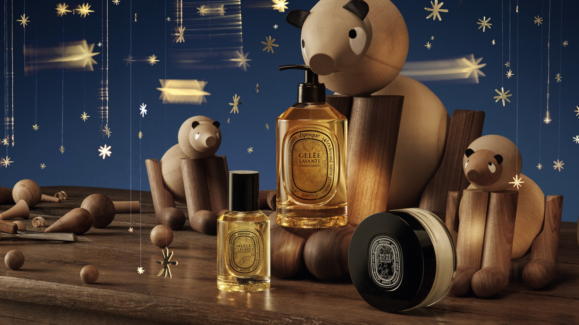Diptyque holiday edition perfume bottles featuring sleek black wood-textured caps and gold embossed labels.