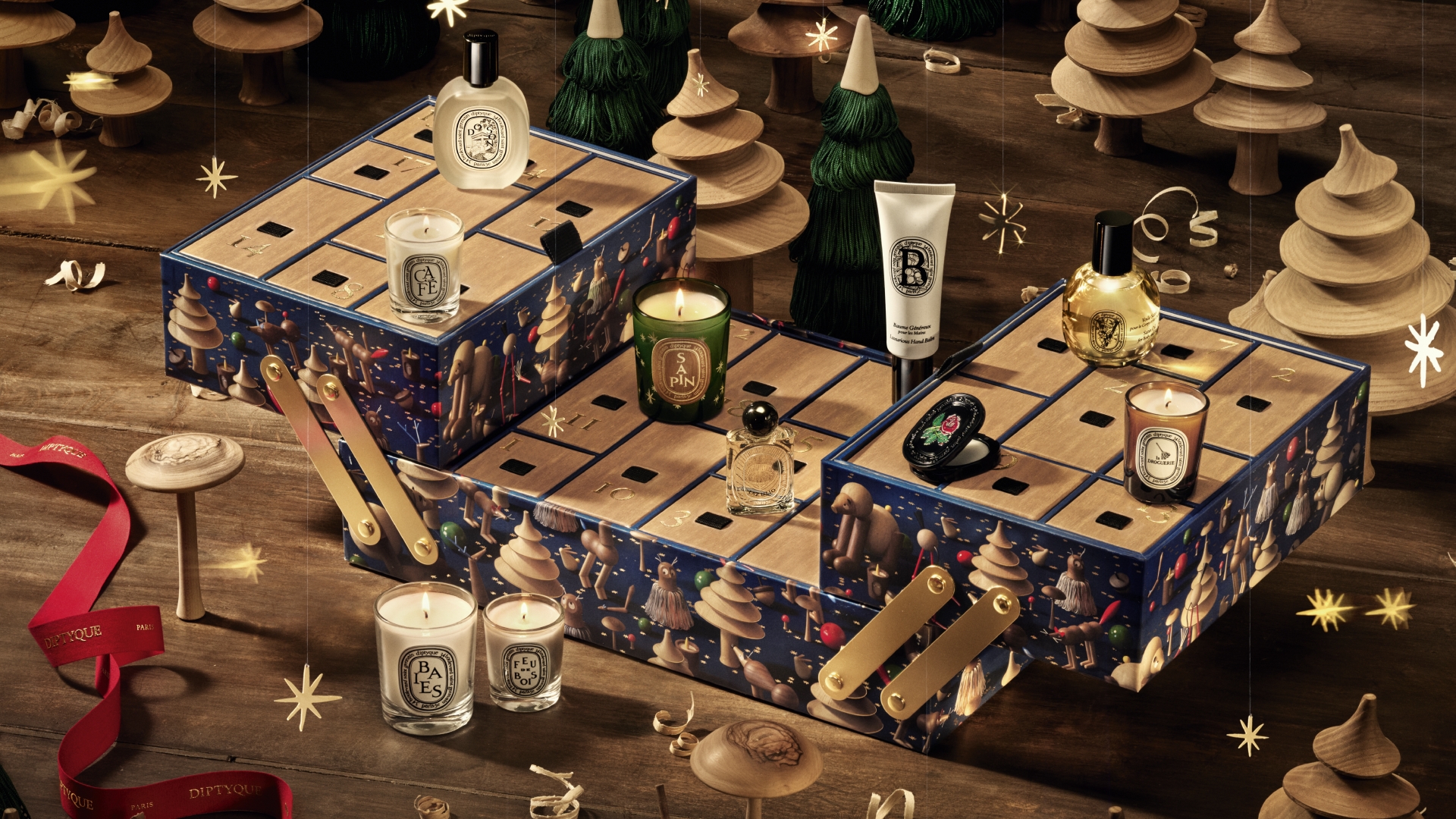 Diptyque's 2026 Advent Calendar designed as a wooden craftsman's toolbox, adorned with whimsical sculpted woodland characters and golden holiday details.