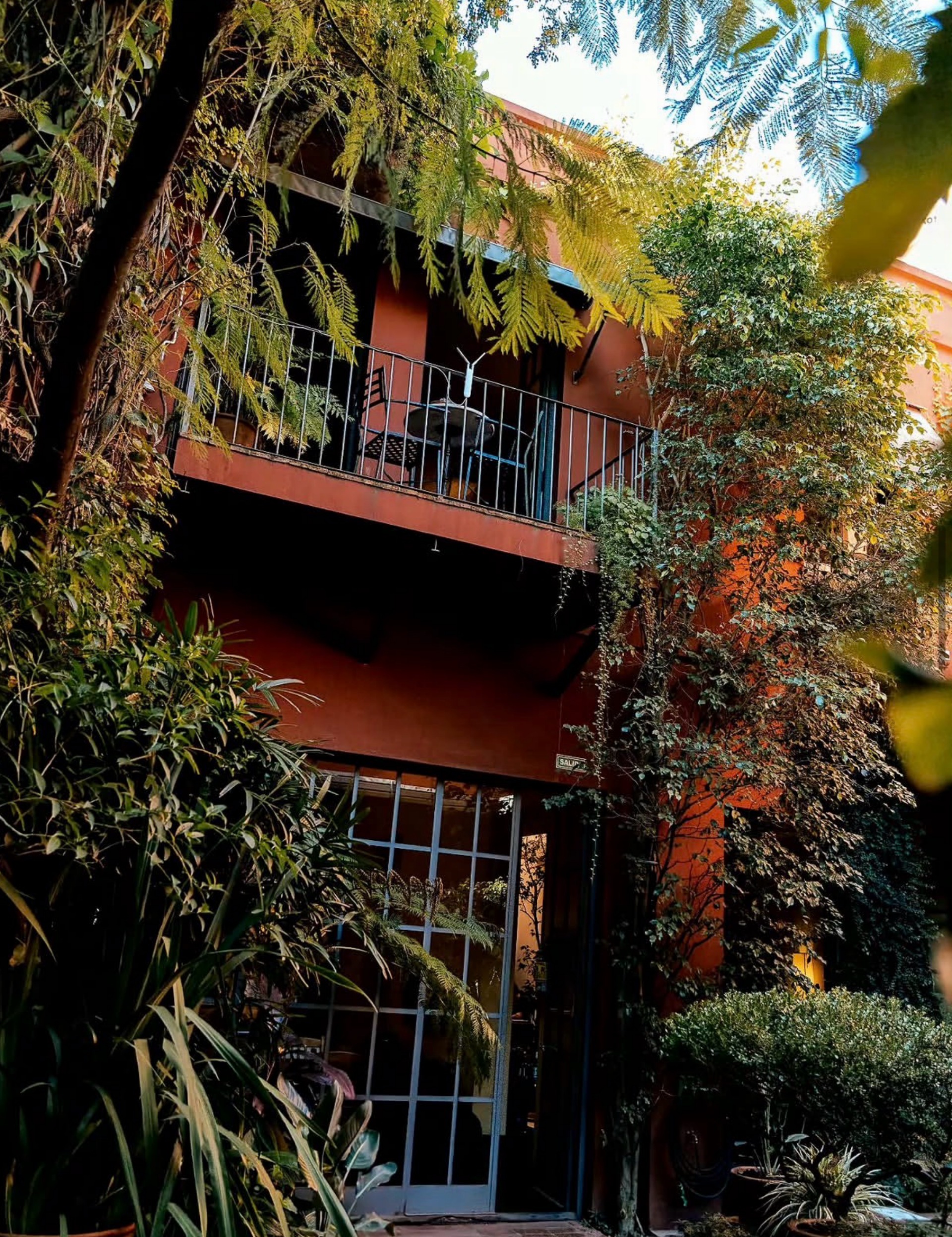 A second-floor balcony overlooking the garden oasis, showing the organic connection between architecture and nature.